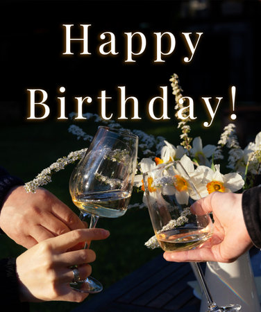 Greeting card design with birthday text, clinking wine glasses, romantic flowers, outdoor dinner mood, soft evening light, seasonal celebration, elegant garden moment, spring summer atmosphereの写真素材