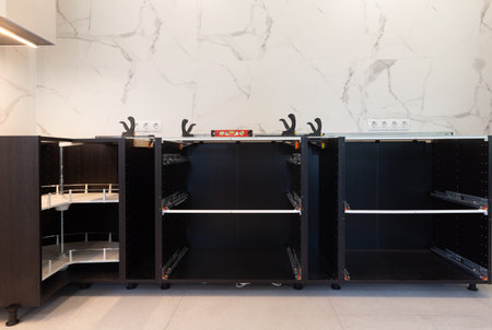 DIY kitchen installation, base cabinets without countertop, open drawers with runners, corner carousel unit, level and clamps on top, marble backsplash, modern renovation, step-by-step assemblyの写真素材