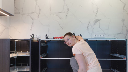 DIY kitchen cabinet installation in modern interior, woman assembling kitchen furniture, home renovation process, DIY kitchen renovation, copy space for designの写真素材