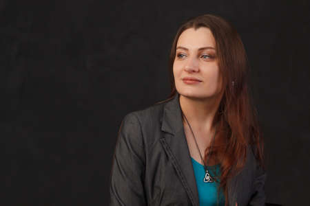 Young woman with dark hair womenwearing a blazer in a dark backgroundのeditorial素材