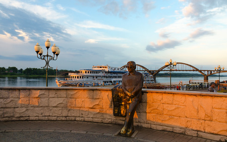 RYBINSK, RUSSIA - JULY 21, 2016: Unidentified people walk in open air near monument to Lev Oshanin on waterfront of Rybinsk at sunsetのeditorial素材