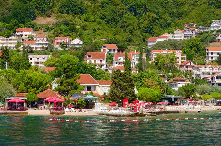 BAOSICI, MONTENEGRO - SEPTEMBER 16, 2015: Beautiful view from sea on coast, Kotor Bay, Montenegro. Unknown people are resting on beach of resort town of Baosiciのeditorial素材