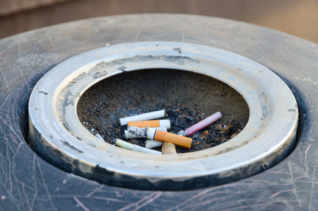 Cigarette butts in ashtray on city street close-upの写真素材