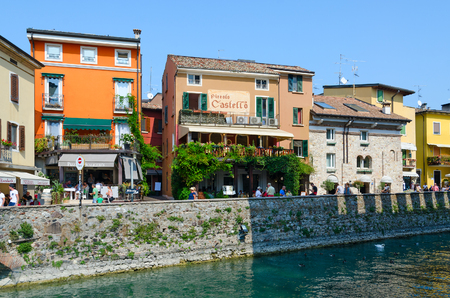 SIRMIONE, ITALY - SEPTEMBER 16, 2018: Unidentified tourists walk along street near Piccolo Castello restaurant in historic center of Sirmione on shore of Lake Garda, Italyのeditorial素材