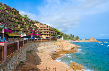 TOSSA DE MAR, SPAIN - SEPTEMBER 12, 2018: Beautiful view of embankment in popular resort town of Tossa de Mar, Costa Brava, Spain. Unknown people walking down streetのeditorial素材