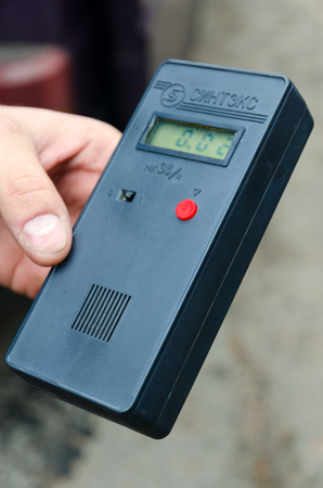 CHERNOBYL, UKRAINE - NOVEMBER 11, 2018: Measurement of radiation background in Chernobyl NPP exclusion zone, Ukraine. Dosimeter in male hand on blurred backgroundのeditorial素材