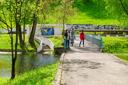 VITEBSK, BELARUS - MAY 21, 2017: Unidentified young people rest and chat on bridge over Vitba River in Park of Culture and Rest named after Frunze on sunny May dayのeditorial素材