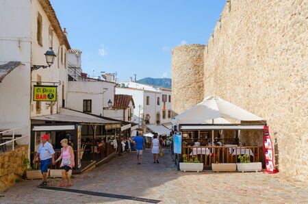 TOSSA DE MAR, SPAIN - SEPTEMBER 12, 2018: Unidentified tourists walk along narrow street in historic center of resort town of Tossa de Mar, Costa Brava, Catalonia, Spainのeditorial素材