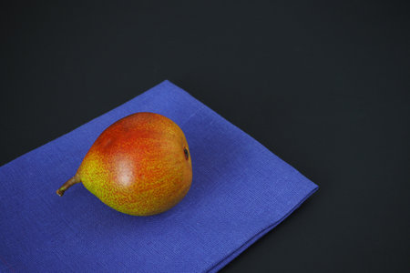 The ripe pear lies on a blue linen napkin. Color photo.の写真素材