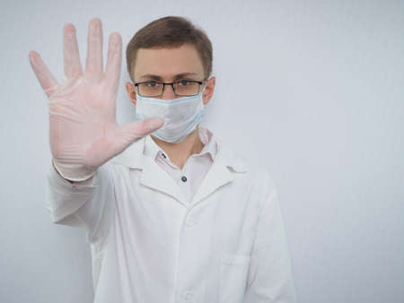 A young doctor of European appearance in medical clothes, a medical mask on his face and gloves. High quality photoの写真素材