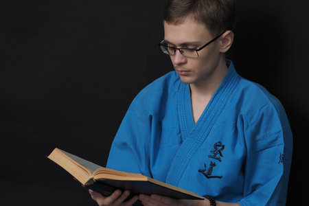 Portrait of a young man of European appearance in a blue kimono, reads a book. High quality photo