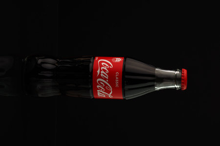 Coca-Cola. A classic glass transparent bottle of Coca-Cola with a red lid, insulated on a black...