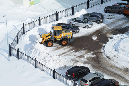 Snow removal equipment. Cleaning of streets and yards from snow. A dump truck loads snow into a...