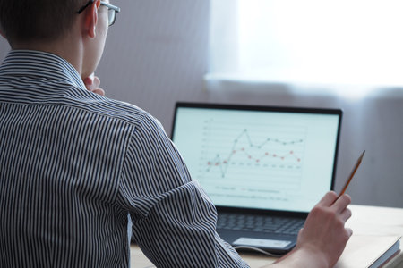 The young man looks at the laptop screen. Remote work, online education. The latest technologies,...