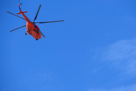 A red helicopter flies high in the blue sky, Aviation. High quality photo