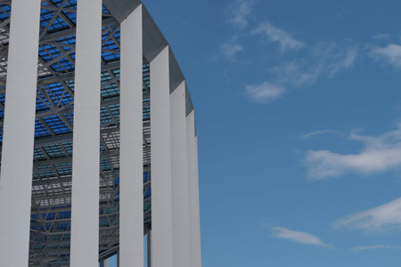 Architecture, modern stadium. A large building with columns and a transparent roof against the blue...