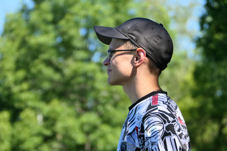 Generation Z. Portrait of a young man of European appearance in glasses and a baseball cap, in the summer on the street. High quality photoの写真素材