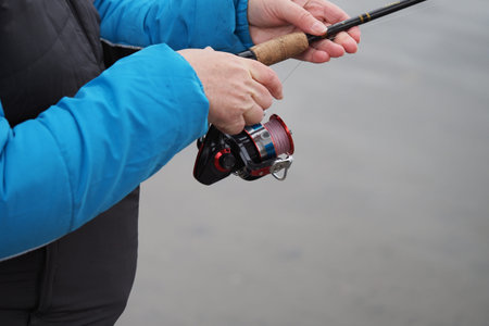 Fishing. A fishing rod with a reel in the hands of a fisherman. Close-up. High quality photoの写真素材