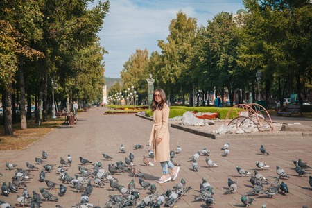 Girl with pigeons in sunglasses on a city alleyの写真素材