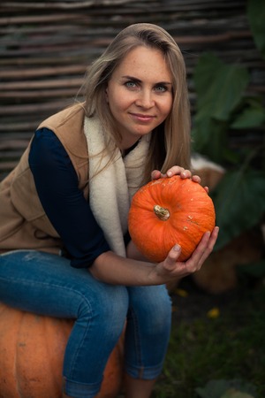 girl sits on a birch stump with the pumpkins. against the backdrop of sunflowersの写真素材