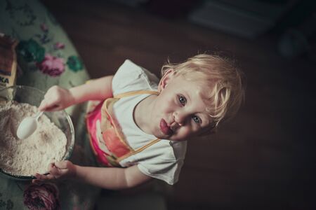 little girl baking cookies. Flour stirred in a cupの写真素材
