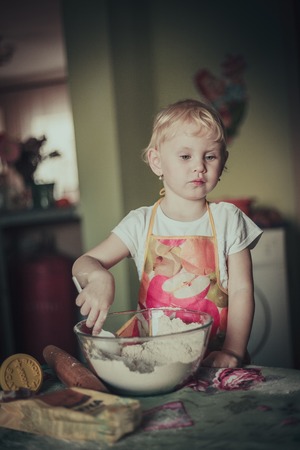 little girl baking cookies. Flour stirred in a cupの写真素材
