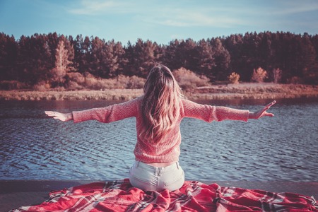 Beautiful girl with book sits on the shore of the lakeの写真素材
