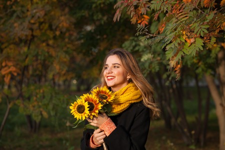 Beautiful girl with sunflowers in the autumn rowanの写真素材