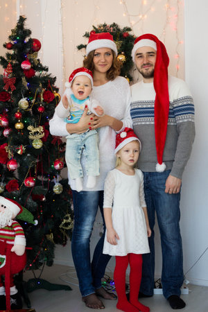 big happy family sitting in Santas caps near the Christmas treeの写真素材