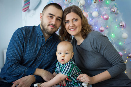 father and mother and son near Christmas tree