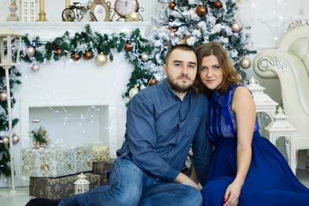 husband and wife in a New Year's tree hall with fireplaceの写真素材