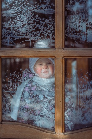 child for icy window on a cold winter dayの写真素材