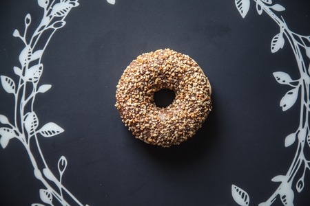 round donut with peanut sprinkles on a black backgroundの写真素材