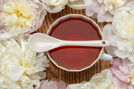 teatime. Flat lay over wooden background with peonies, cup of tea and spoon. wedding or birthday conceptionの写真素材