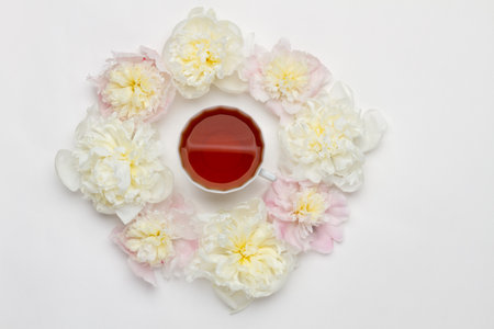 teatime. Flat lay over white background with peonies and cup of tea. wedding or birthday conceptionの写真素材