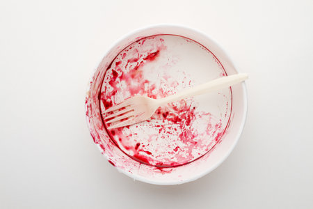 Dirty disposable bowl and fork after eating on a white background.の写真素材