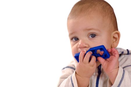 Baby with blue eyes chewing blue toy isolated on whiteの写真素材