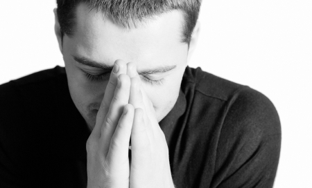 Young man praying with eyes closed closeup isolated on whiteの写真素材