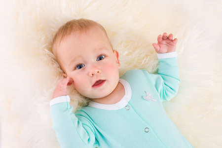 Baby Portrait looking straight at you lying on white fluffy fur