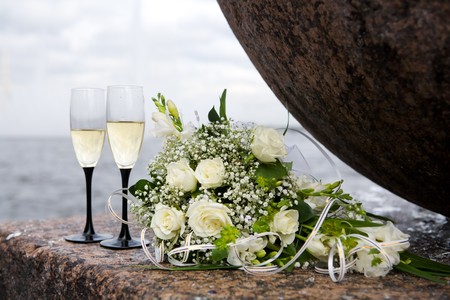 wedding bouquet and two champagne glasses outdoorsの写真素材