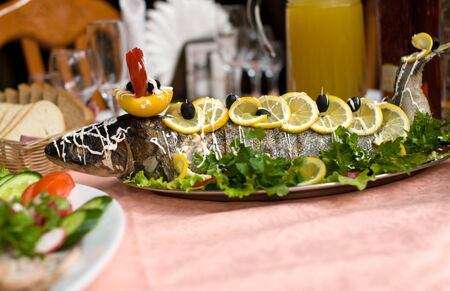 baked fish full body on plate in restaurantの写真素材