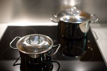 Two new stainless steel saucepans on modern kitchen rangeの写真素材
