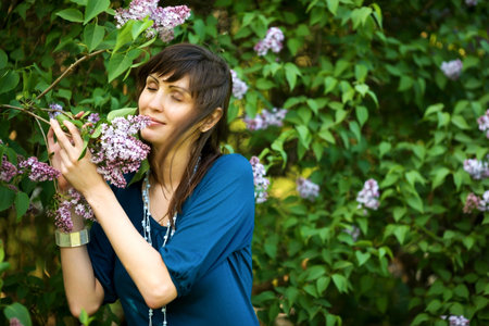 Young woman smelling lilac in spring parkの写真素材