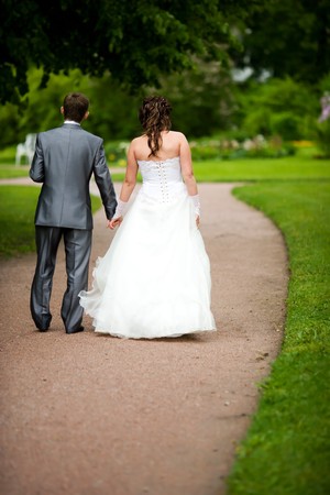 Bride and groom walking away in summer park outdoorsの写真素材