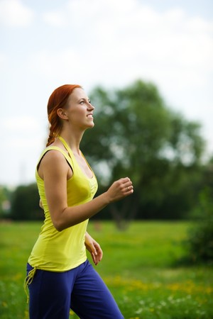 Young woman jogging looking up summer meadowの写真素材