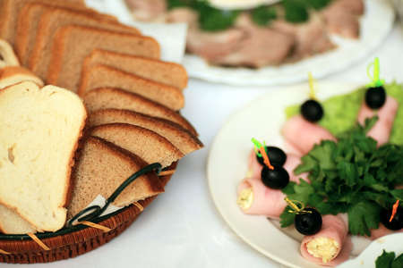 Sliced bread and ham rolls with olives on tableの写真素材