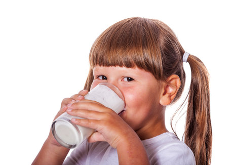 Six years Girl holding glass of milk isolated on whiteの写真素材