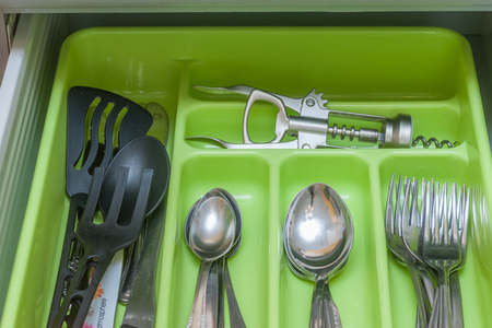 Green silverware drawer with forks spoons and other  kitchenwareの写真素材