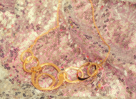 Beautiful shiny golden asymmetric necklace with different circle forms over silver background