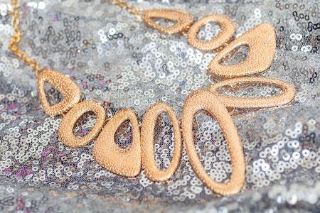 Beautiful shiny golden asymmetric necklace with different circle forms over silver backgroundの写真素材